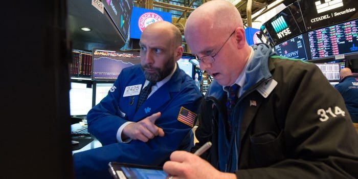 Dois operadores de ações na Bolsa de Valores de Nova York analisando uma tela